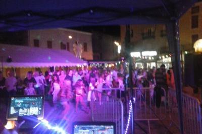 Des artistes en costumes brillants dansent sur une scène illuminée par des projecteurs colorés et un écran lumineux.