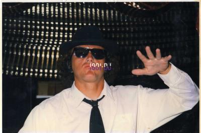 Des artistes en costumes brillants dansent sur une scène illuminée par des projecteurs colorés et un écran lumineux.