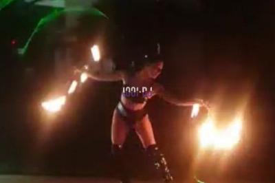 Des artistes en costumes brillants dansent sur une scène illuminée par des projecteurs colorés et un écran lumineux.