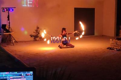 Des artistes en costumes brillants dansent sur une scène illuminée par des projecteurs colorés et un écran lumineux.