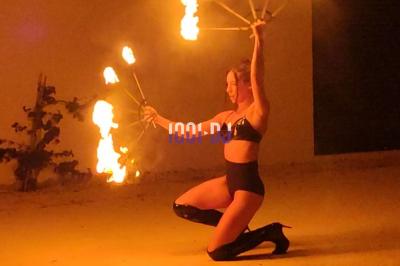 Des artistes en costumes brillants dansent sur une scène illuminée par des projecteurs colorés et un écran lumineux.