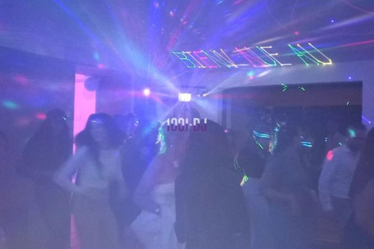 Personnes dansant dans une salle sombre éclairée par des lumières colorées et des effets laser.