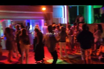 Des artistes en costumes brillants dansent sur une scène illuminée par des projecteurs colorés et un écran lumineux.