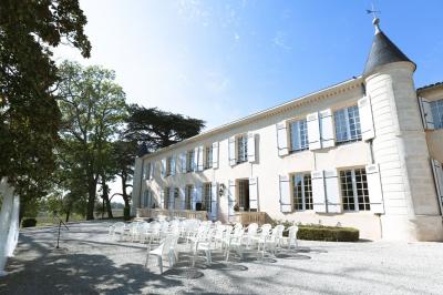 Chambre lumineuse avec murs en toile de Jouy rouge, mobilier classique, table basse et fauteuils près d'une fenêtre.