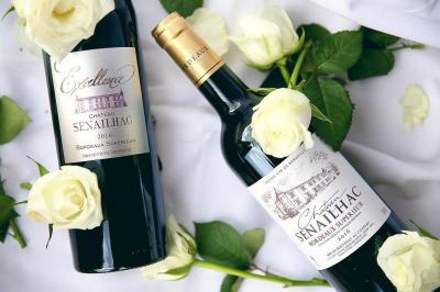 Chambre lumineuse avec murs en toile de Jouy rouge, mobilier classique, table basse et fauteuils près d'une fenêtre.