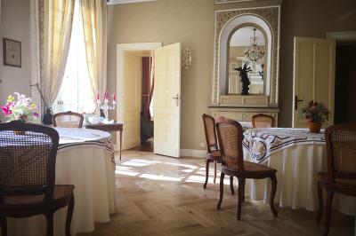 Chambre lumineuse avec murs en toile de Jouy rouge, mobilier classique, table basse et fauteuils près d'une fenêtre.