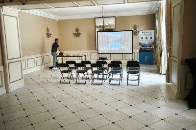 Chambre lumineuse avec murs en toile de Jouy rouge, mobilier classique, table basse et fauteuils près d'une fenêtre.