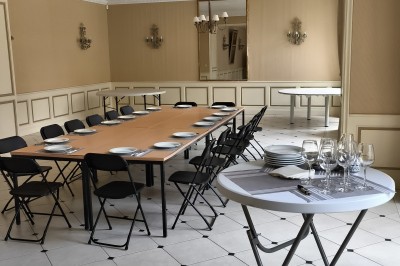 Chambre lumineuse avec murs en toile de Jouy rouge, mobilier classique, table basse et fauteuils près d'une fenêtre.