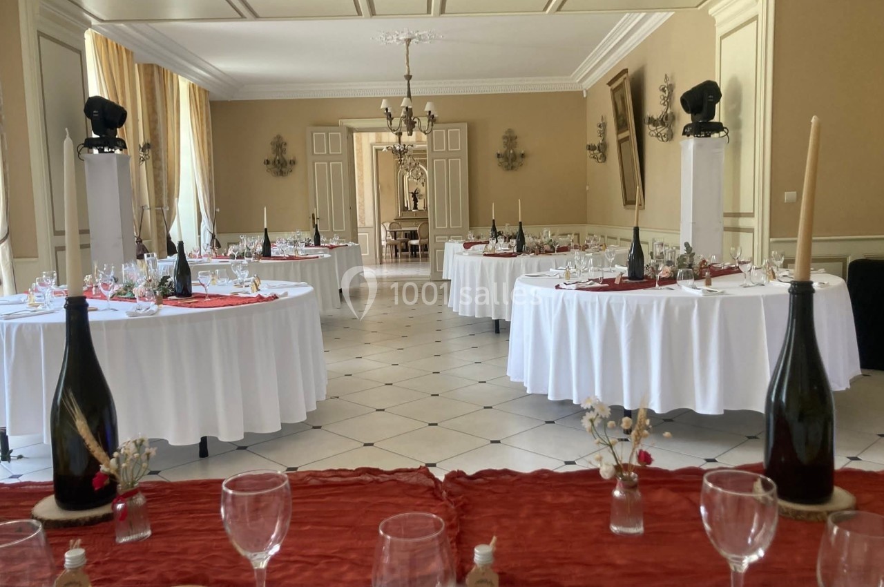 Salle de réception élégante avec tables rondes dressées, nappes blanches et décorations raffinées.