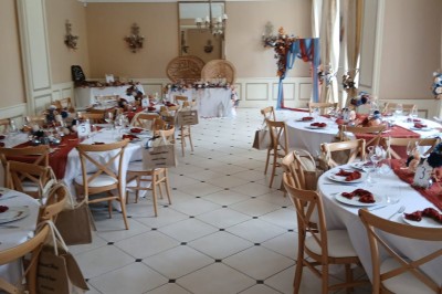 Façade claire avec volets blancs, lanterne en fer forgé et jardinières de fleurs roses en premier plan.
