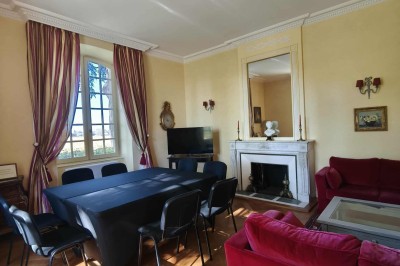 Façade claire avec volets blancs, lanterne en fer forgé et jardinières de fleurs roses en premier plan.