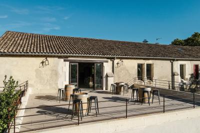 Personnes assises à des tables en plein air dans un jardin, entourées de verdure et de guirlandes lumineuses suspendues.