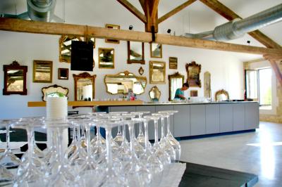 Personnes assises à des tables en plein air dans un jardin, entourées de verdure et de guirlandes lumineuses suspendues.
