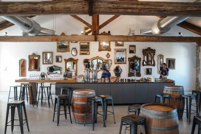 Personnes assises à des tables en plein air dans un jardin, entourées de verdure et de guirlandes lumineuses suspendues.