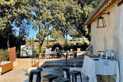 Personnes assises à des tables en plein air dans un jardin, entourées de verdure et de guirlandes lumineuses suspendues.