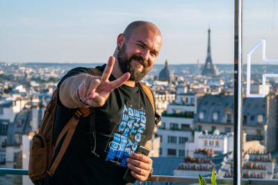 Trois hommes souriants posent ensemble dans un espace professionnel lors d'un événement, badges autour du cou.