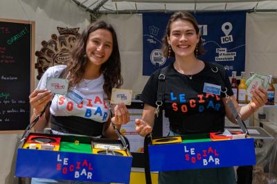 Miniature Social Bar #1 Une personne tient un jeu coloré avec une roue et des compartiments, marqué ’Le Social Bar’.