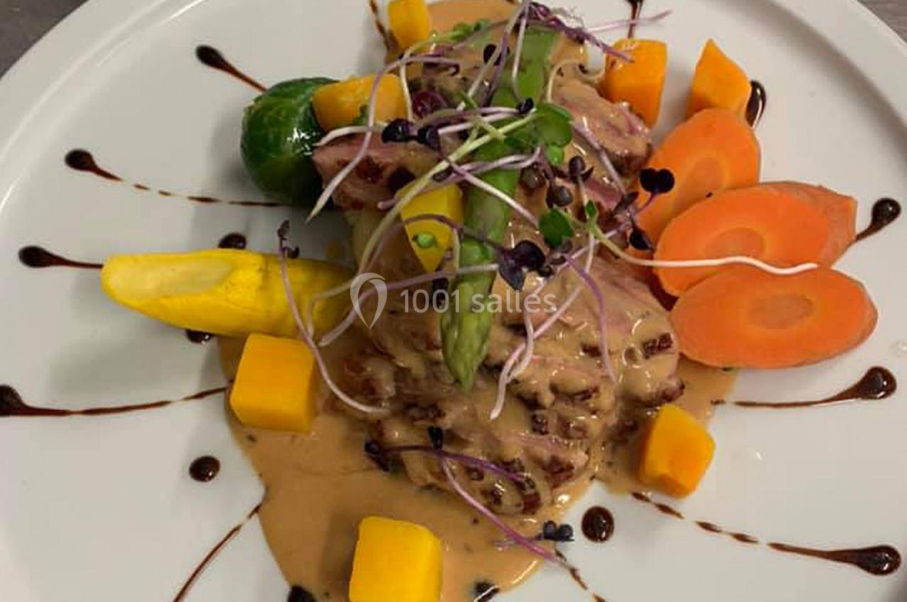 Assiette gastronomique composée de viande, légumes colorés, sauce crémeuse et décorations de réduction balsamique.