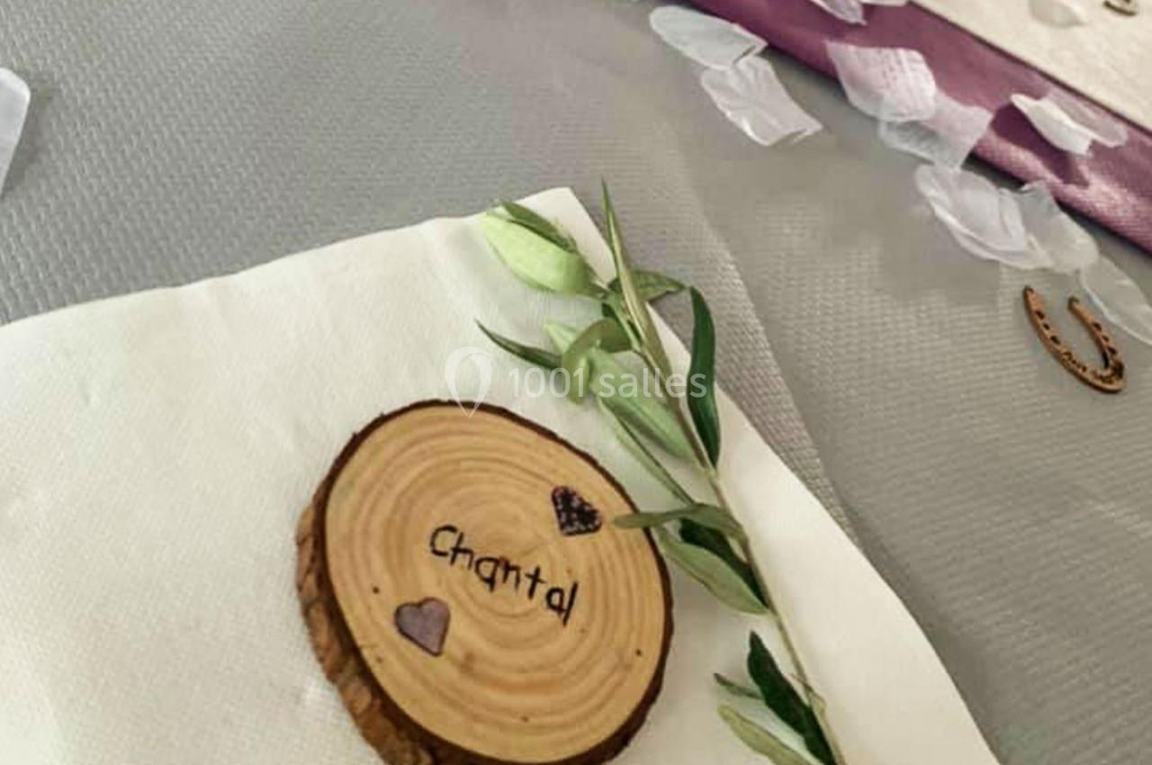 Rondin de bois gravé ’Chantal’ avec des cœurs, posé sur une serviette blanche avec une branche d'olivier.