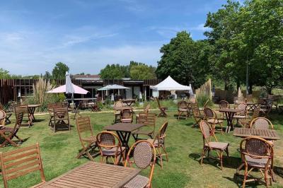Table dressée en extérieur avec nappes blanches, fleurs en centre de table, parasols roses et verdure en arrière-plan.