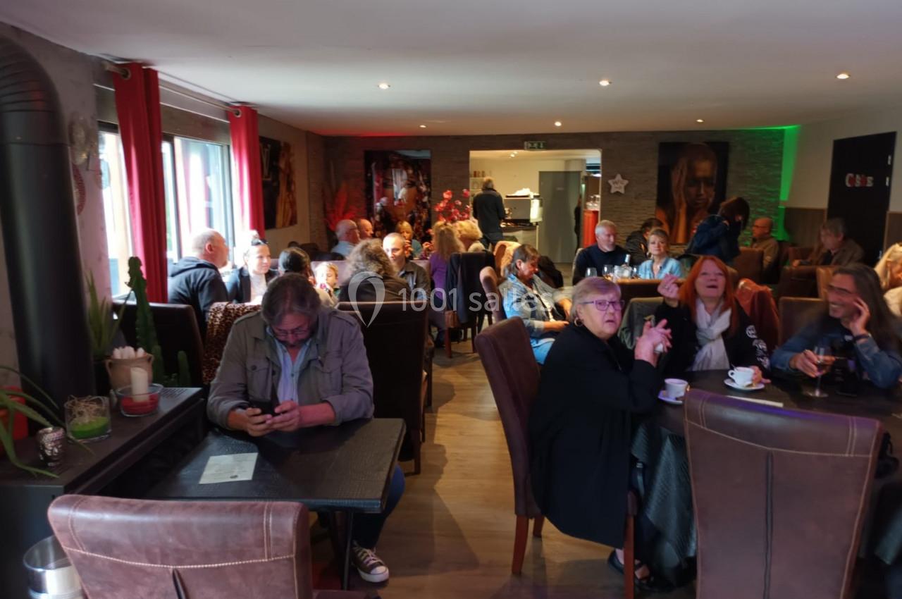 Des personnes assises dans un café, discutant ou utilisant leur téléphone, dans une ambiance conviviale.