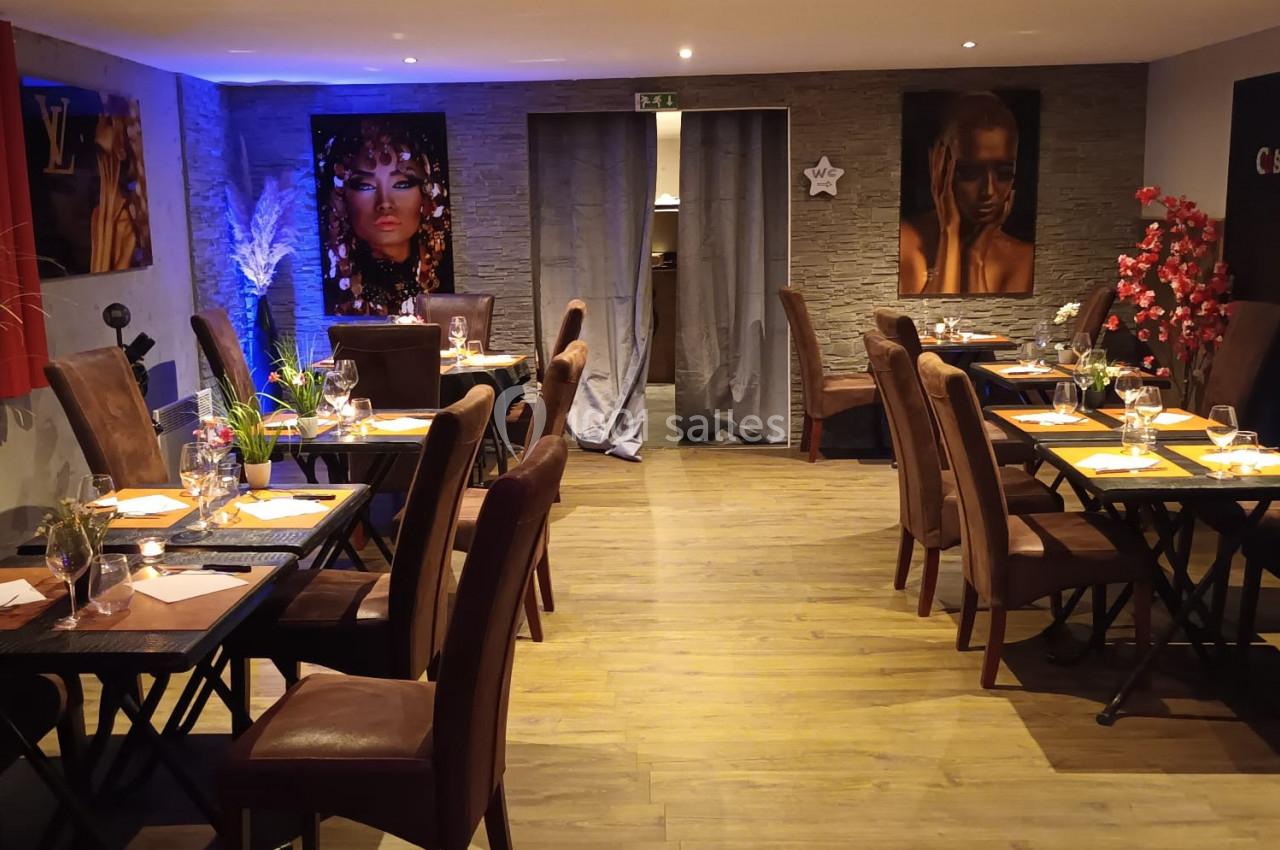 Salle de restaurant chaleureuse avec tables dressées, éclairage tamisé et décorations murales colorées.