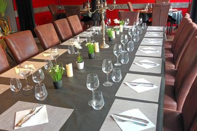 Table dressée en extérieur avec nappes blanches, fleurs en centre de table, parasols roses et verdure en arrière-plan.
