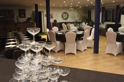 Table dressée en extérieur avec nappes blanches, fleurs en centre de table, parasols roses et verdure en arrière-plan.