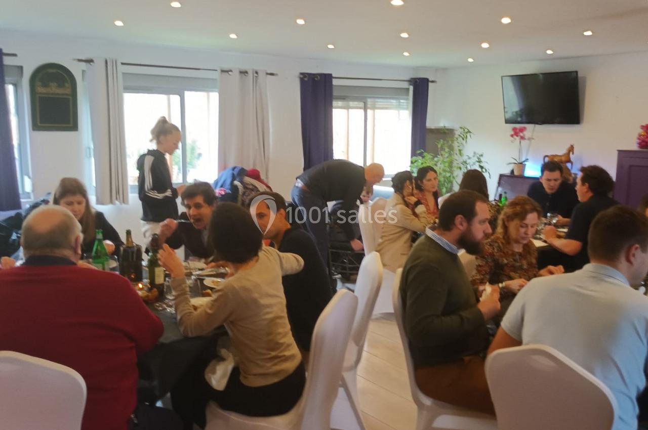 Des personnes assises autour de tables dans une salle lumineuse, partageant un repas convivial.
