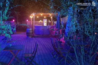 Table dressée en extérieur avec nappes blanches, fleurs en centre de table, parasols roses et verdure en arrière-plan.