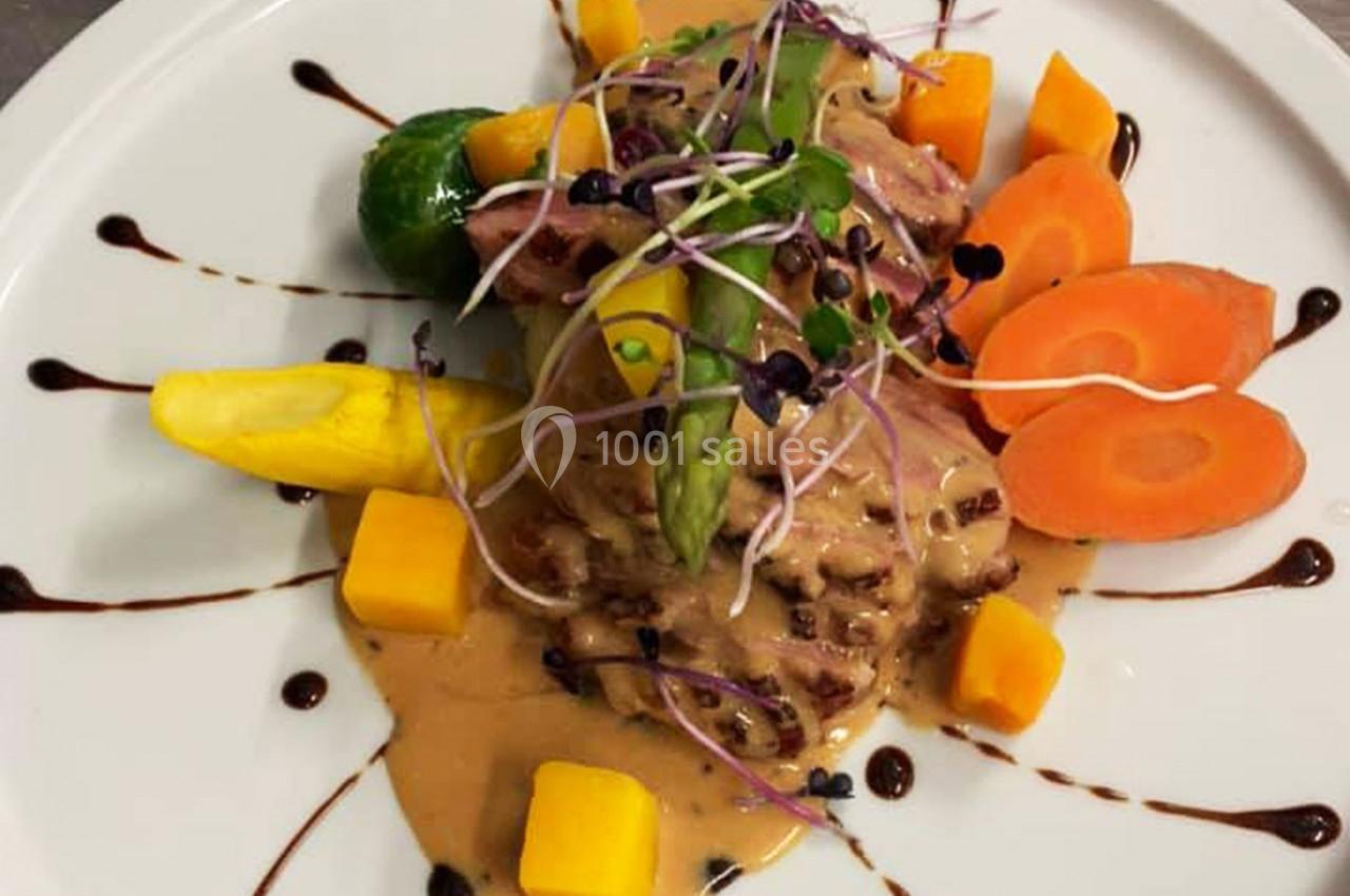 Assiette gastronomique avec viande en sauce, légumes colorés, asperge, germes et filet de réduction balsamique.