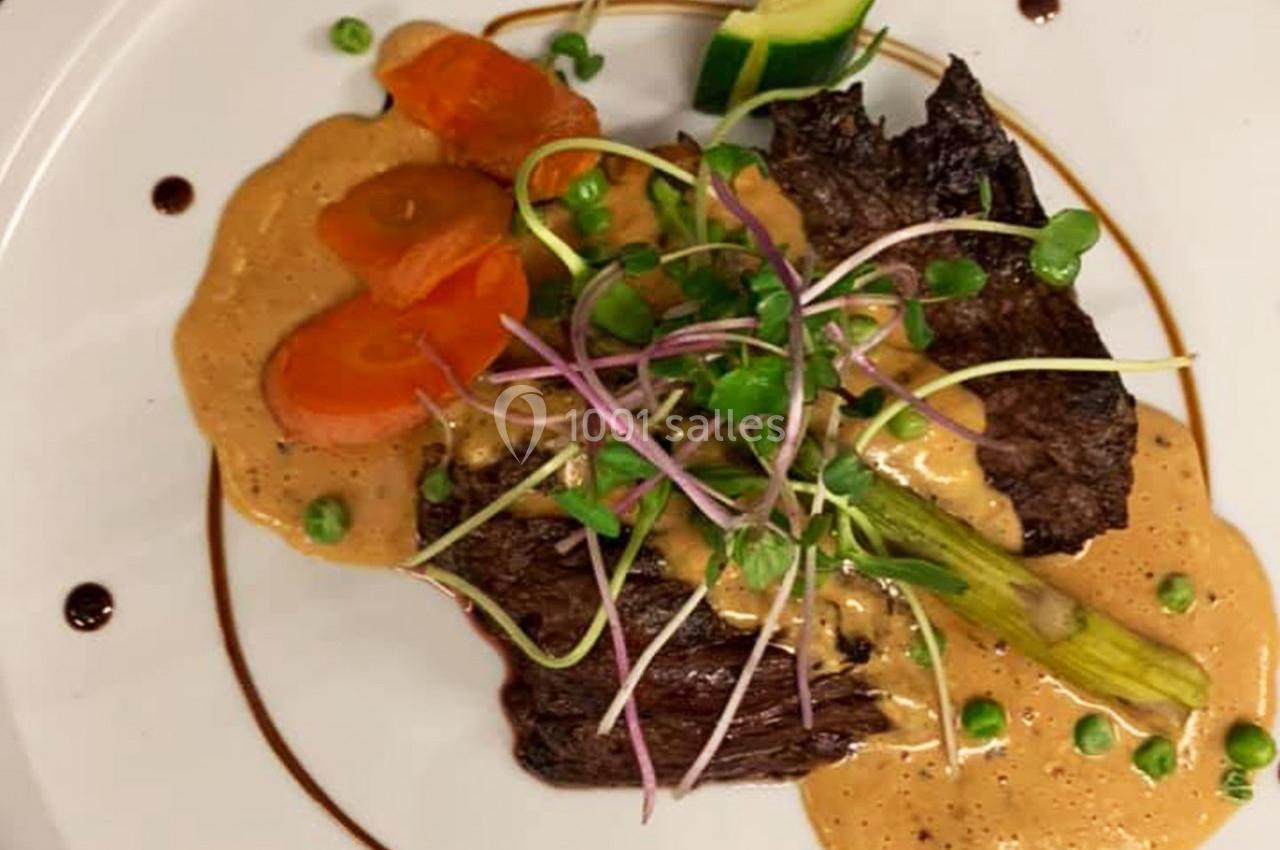 Assiette garnie de viande, carottes, asperges, petits pois, sauce crémeuse et décoration de pousses fraîches.