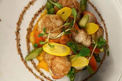 Table dressée en extérieur avec nappes blanches, fleurs en centre de table, parasols roses et verdure en arrière-plan.