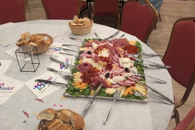 Gâteau rectangulaire décoré de fruits rouges et de cœurs en sucre, posé sur une table en bois.