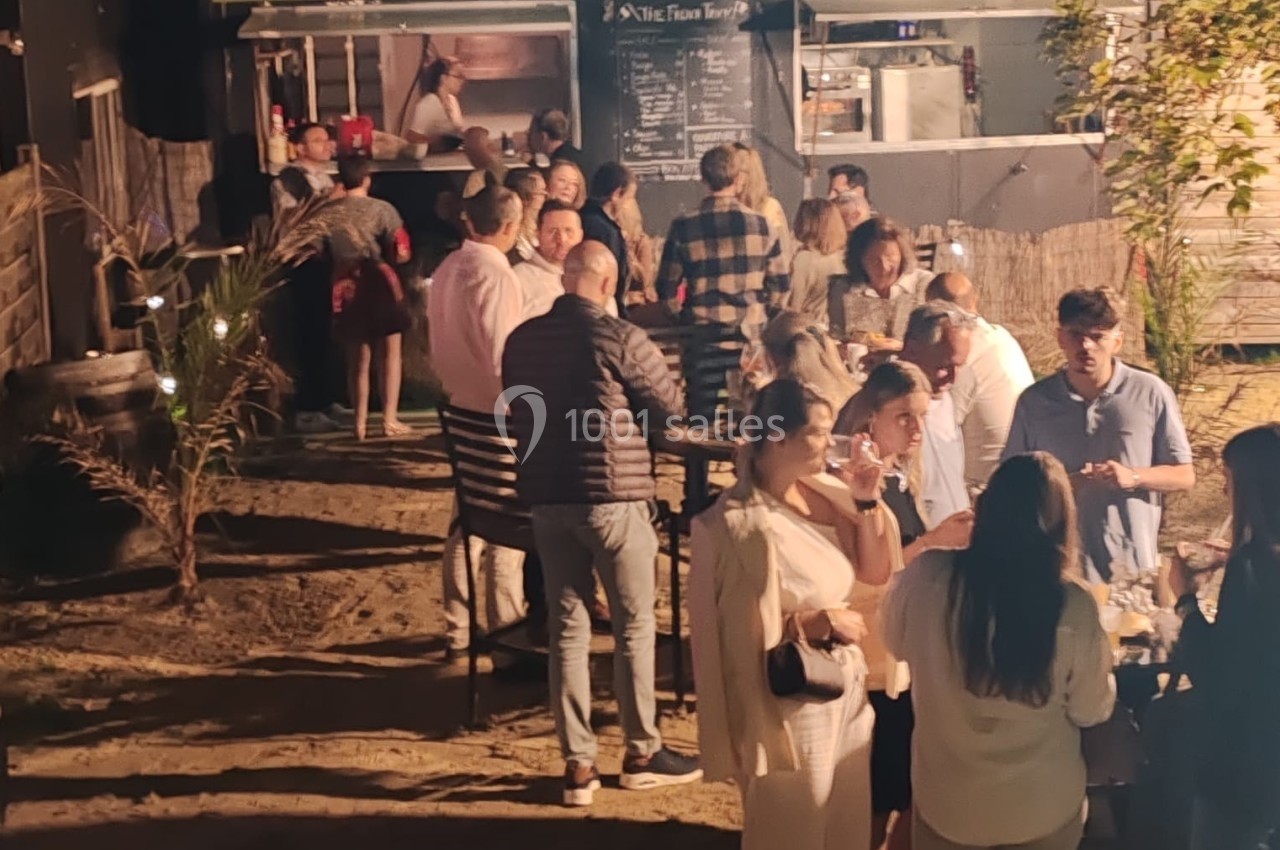Groupe de personnes rassemblées en soirée devant un food truck éclairé, dans un cadre extérieur convivial.