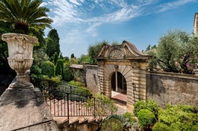 Jardin éclairé de nuit avec piscine, terrasse en pierre et bâtiments entourés de végétation.
