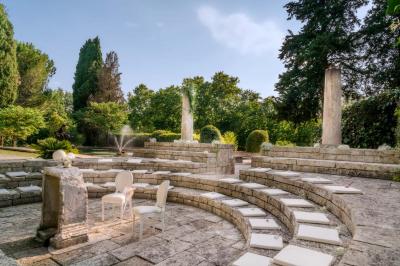 Jardin éclairé de nuit avec piscine, terrasse en pierre et bâtiments entourés de végétation.