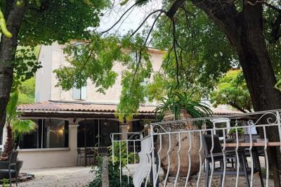 Jardin verdoyant avec pelouse, arbres et buissons, entourant une petite clairière circulaire en béton.