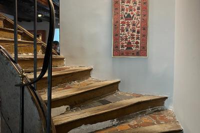 Cour intérieure aménagée avec des poufs colorés, des tables en bois et des guirlandes lumineuses suspendues.