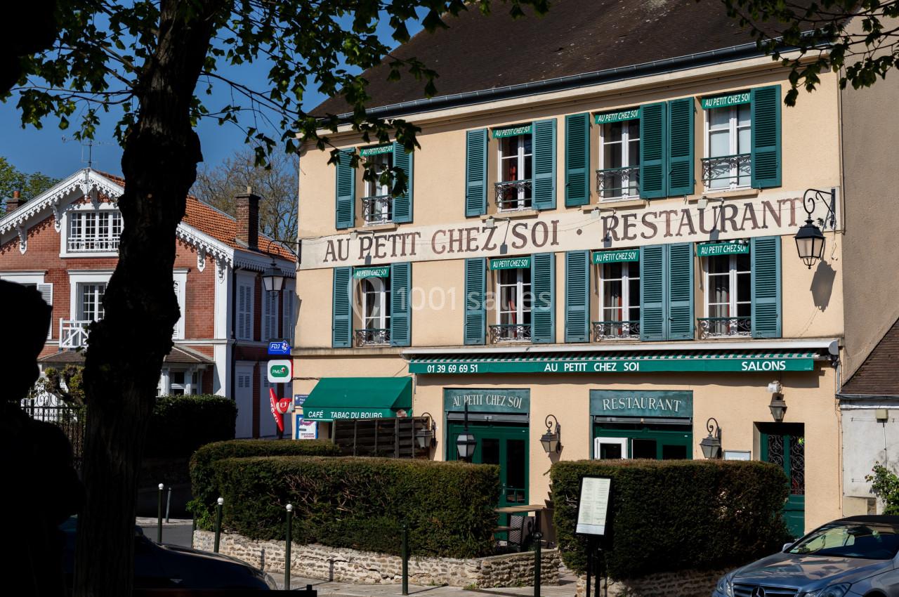 Façade d'un restaurant traditionnel avec volets verts, enseigne ’Au Petit Chez Soi’, entouré de végétation.