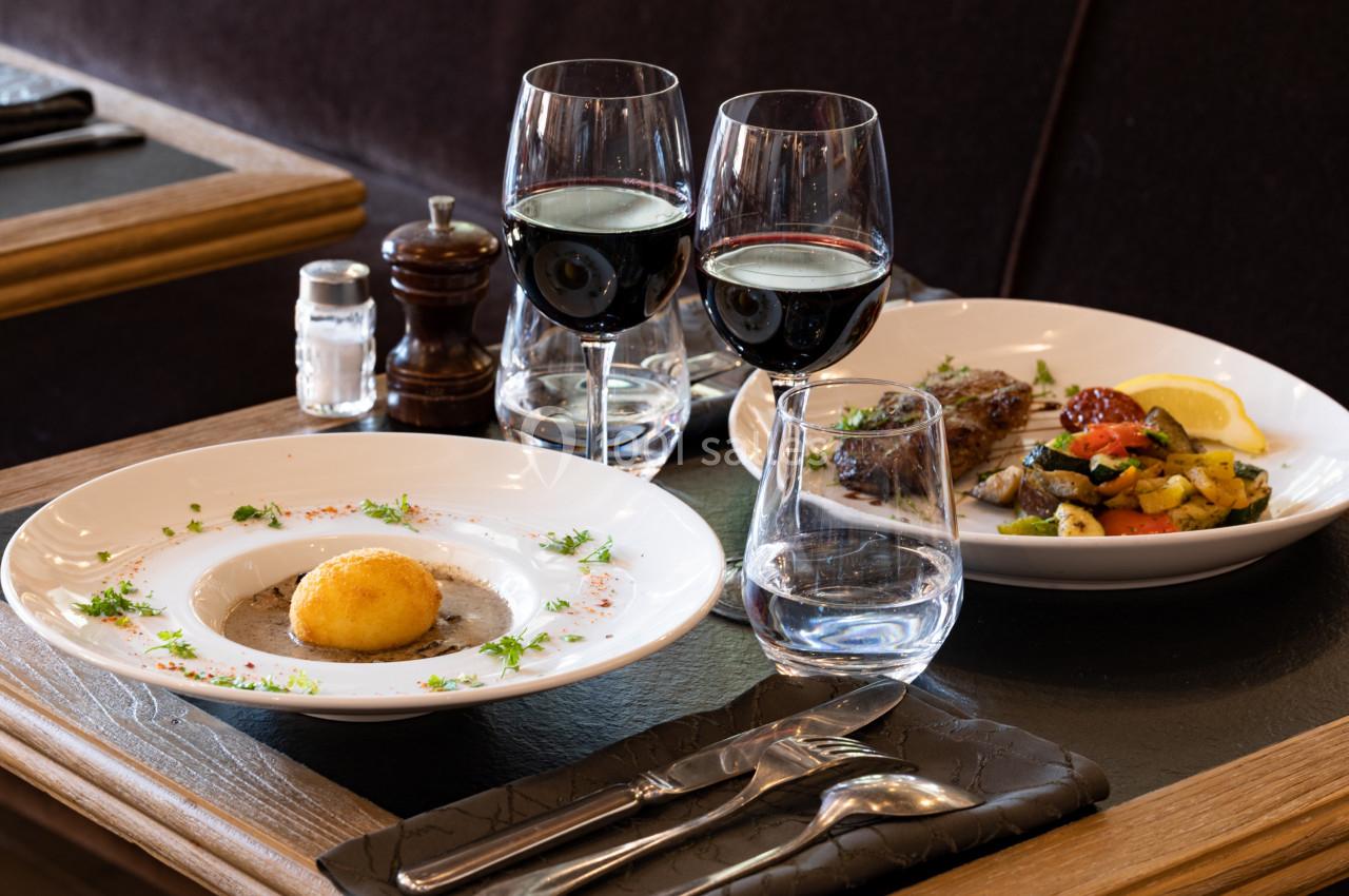 Deux assiettes de plats raffinés avec des verres de vin rouge, disposés sur une table élégamment dressée.