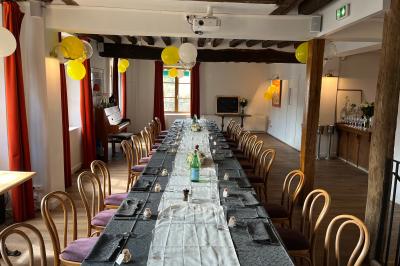 Cour intérieure aménagée avec des poufs colorés, des tables en bois et des guirlandes lumineuses suspendues.