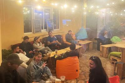 Cour intérieure aménagée avec des poufs colorés, des tables en bois et des guirlandes lumineuses suspendues.