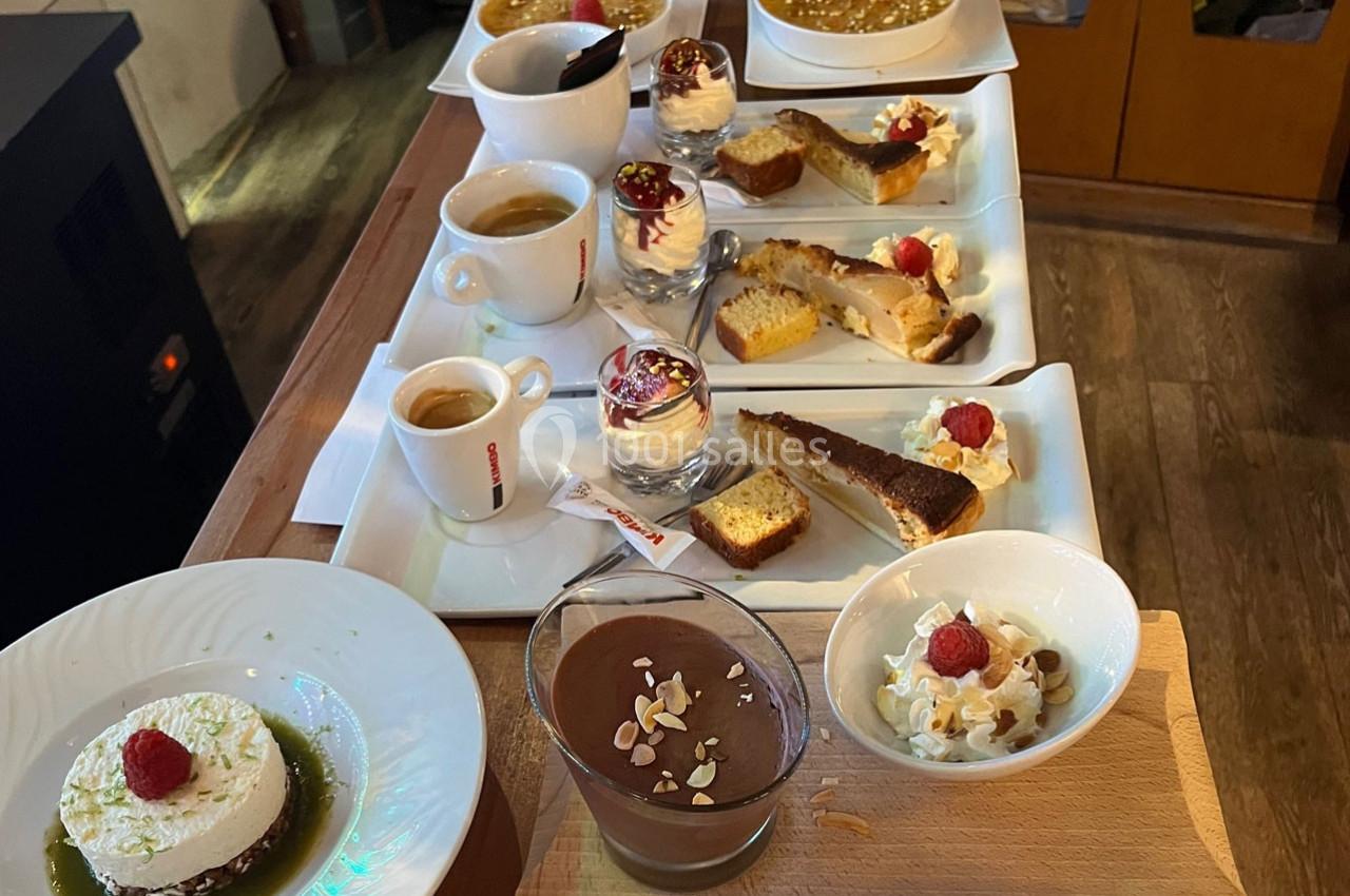 Assortiment de desserts variés comprenant crèmes, gâteaux, mousses et cafés, présentés sur une table en bois.