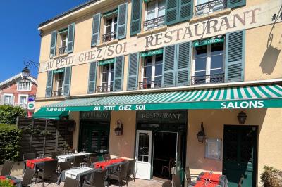 Cour intérieure aménagée avec des poufs colorés, des tables en bois et des guirlandes lumineuses suspendues.