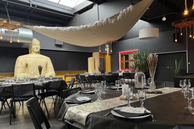 Salle de réception décorée avec des tables dressées, une grande statue et un tissu suspendu au plafond.