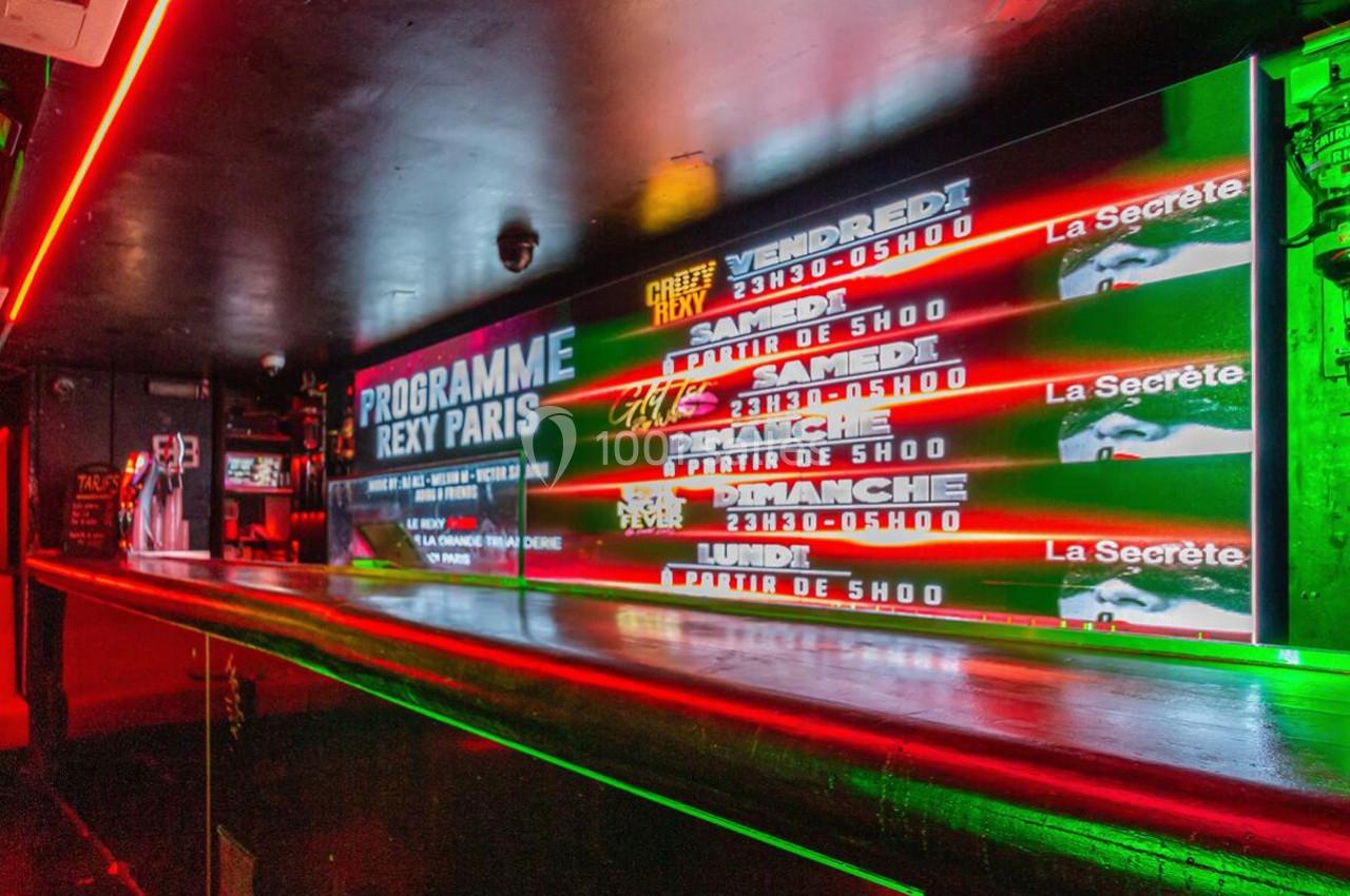 Affiche lumineuse dans un club nocturne présentant le programme des soirées avec horaires et noms des événements.