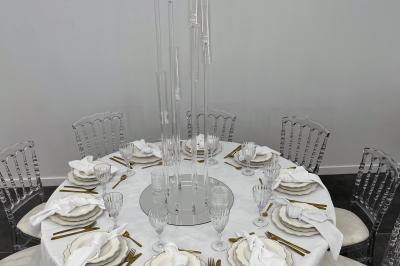 Canapé beige avec décorations dorées, tables basses et chaises blanches dans une salle ornée de panneaux lumineux bleus.