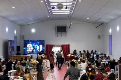 Canapé beige avec décorations dorées, tables basses et chaises blanches dans une salle ornée de panneaux lumineux bleus.