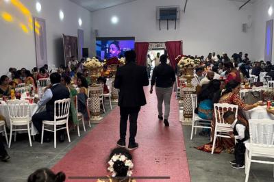 Canapé beige avec décorations dorées, tables basses et chaises blanches dans une salle ornée de panneaux lumineux bleus.